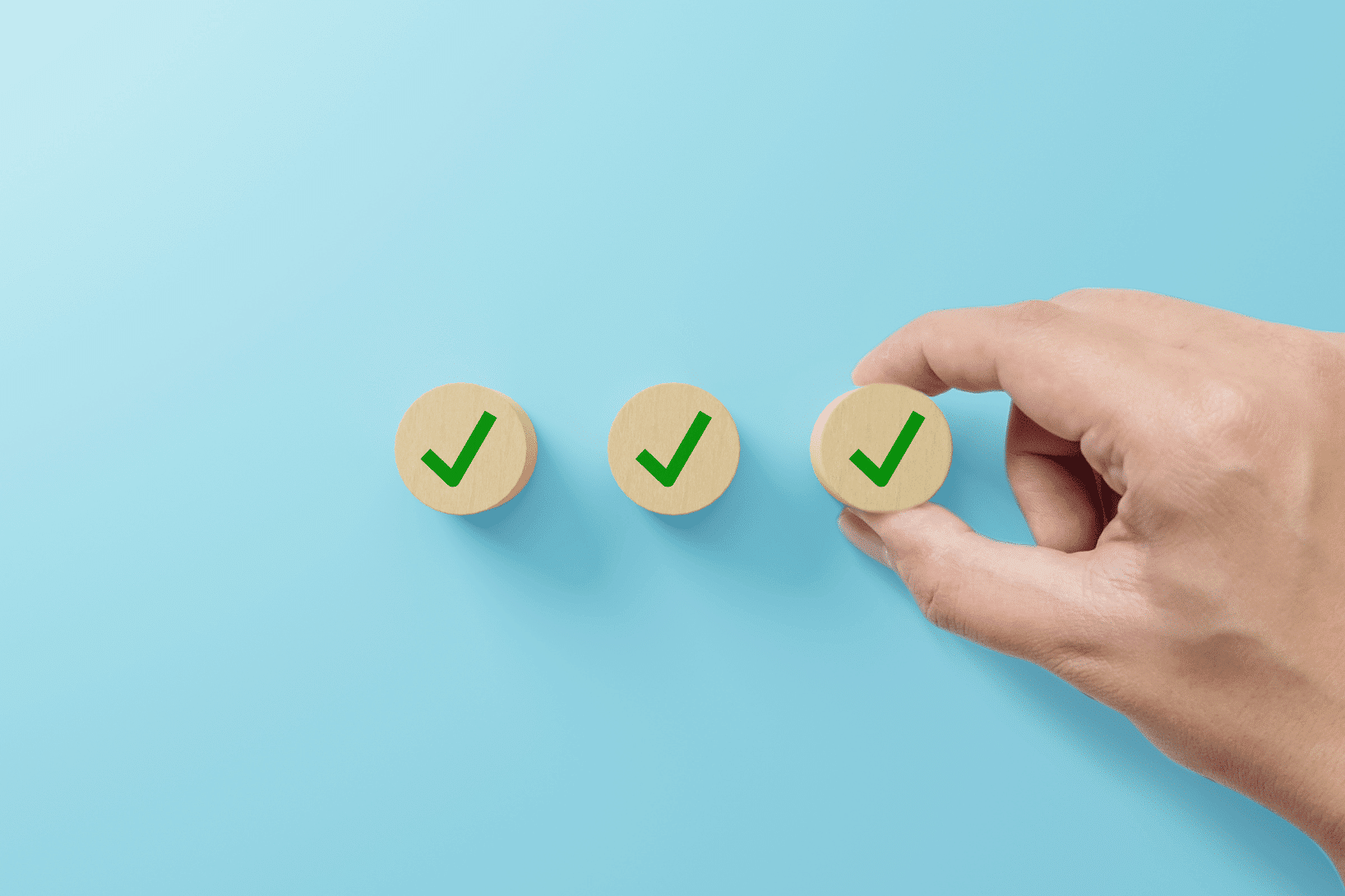 hand placing a checkmark token alongside validated checklist items, representing clinical trial database and CRF validation processes