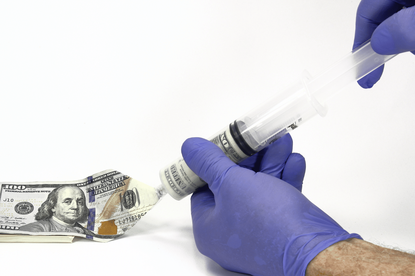 gloved hands holding a syringe containing U.S. currency, representing the rising costs of clinical trials and medical research