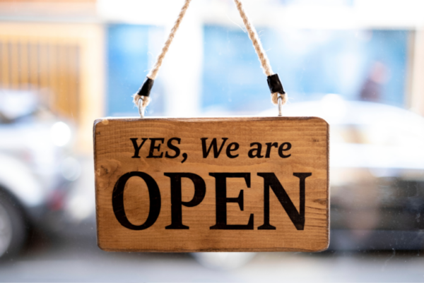 wooden hanging window sign that says 'yes, we are open'